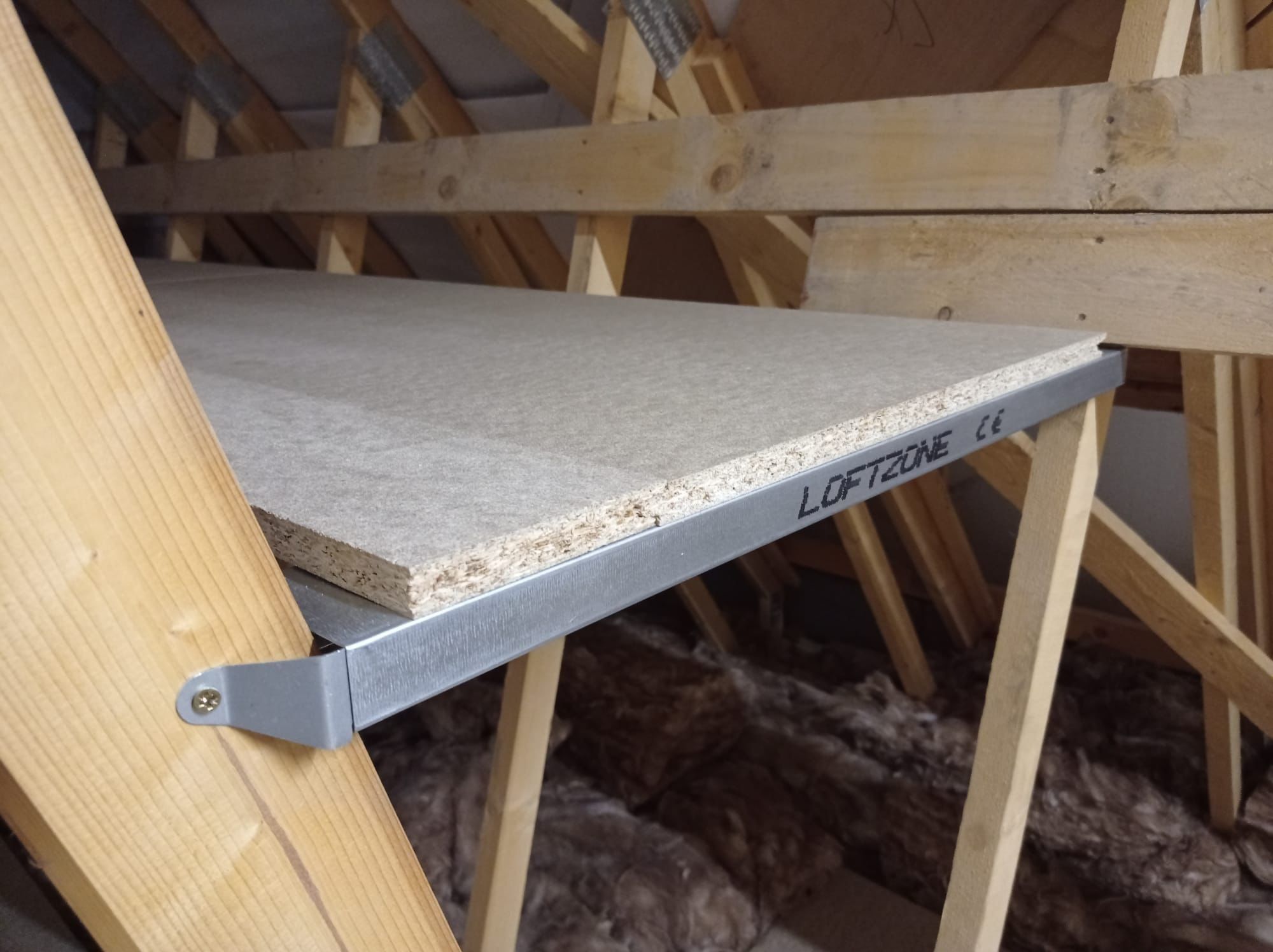 A loft shelf that has been attached between trusses with metal brackets.