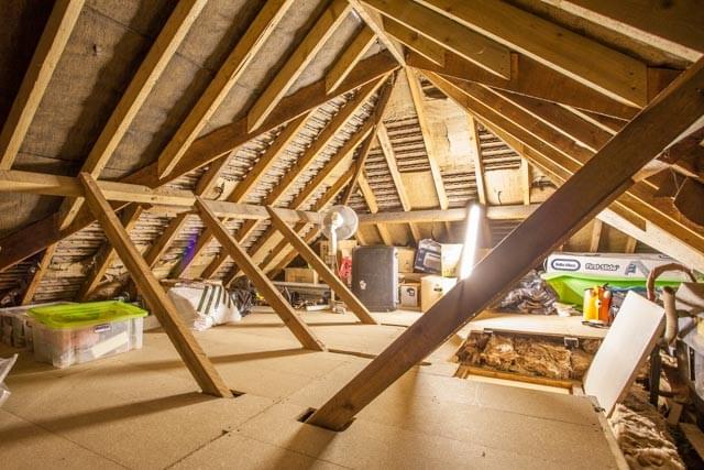 A large loft with a boarded floor, multiple support pillars and LED loft lighting.